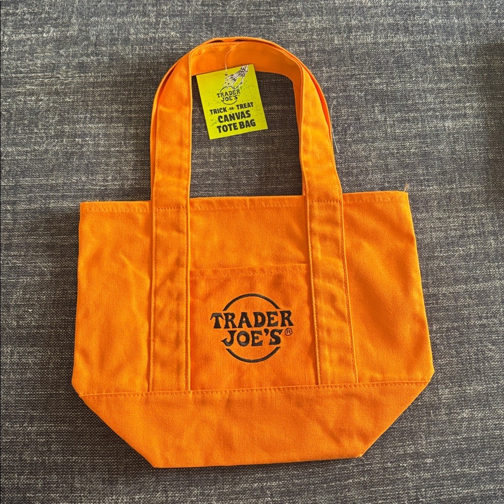NWT Trader Joe’s Halloween Trick or Treat mini tote orange w/ black logo in hand
